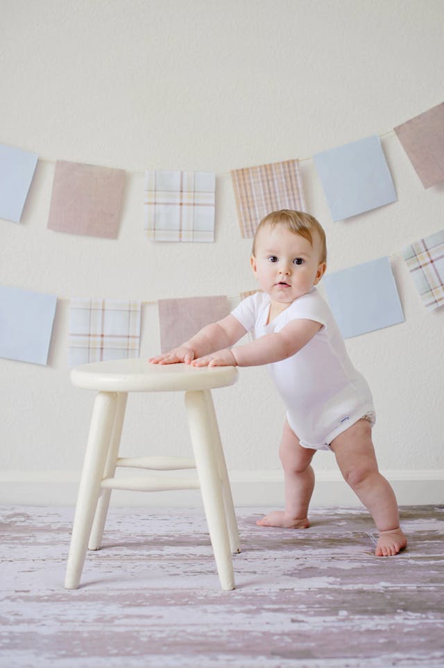 baby standing with chair in front of her